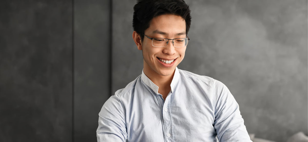 A man smiling while working on a laptop, staying mentally sharp and focused after a late night